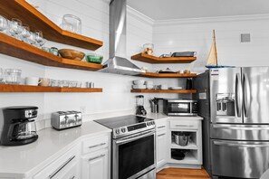 A modern kitchen with white cabinetry, stainless steel appliances, wooden shelves, and a built-in oven. - Luxury 4-Br Vacation Home w/ Matchless Gulf Views +Free Attraction Tickets! (Santa Rosa Beach)