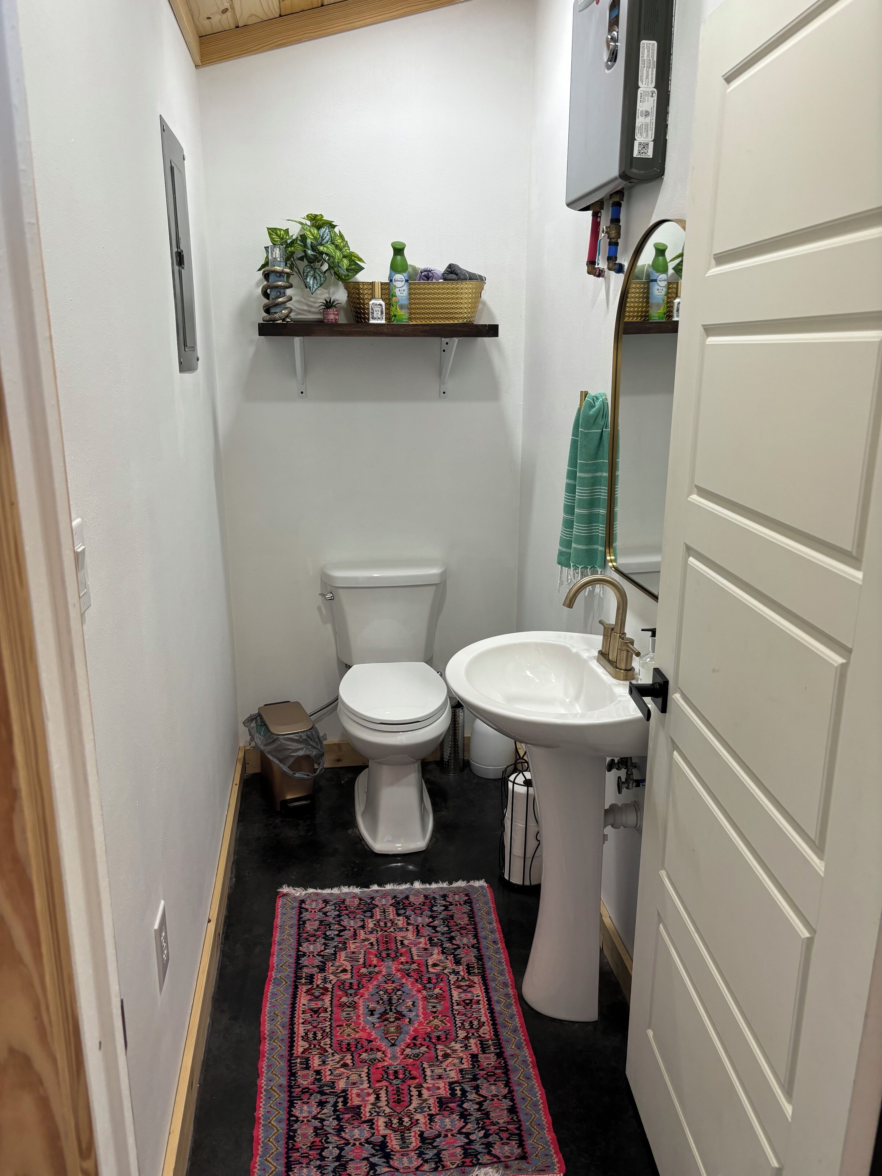 A compact bathroom with a toilet, sink, and a small shelf with toiletries.