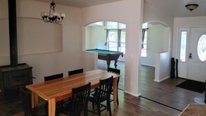 Ein Essbereich mit Holztisch und Stühlen, einem Billardtisch und einem Kamin.