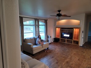 A living room with a beige sofa, a television, and a ceiling fan.