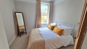 A bedroom with a bed, a mirror, and a window with curtains. - Brylie House, Large Central Family Home (Skipton)
