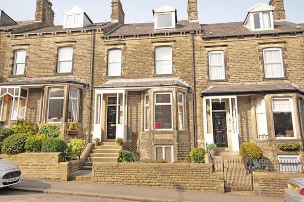 A row of terraced houses with front doors, windows, and steps leading to the entrance.