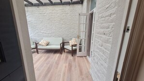 A room with a stone wall, a wooden bench with cushions, and a door with glass panels. - Brylie House, Large Central Family Home (Skipton)