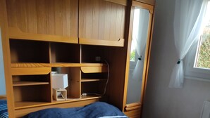 Ein Schlafzimmer mit Bett, Holzschrank und Nachttisch.