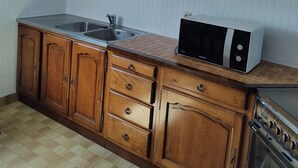 Eine Küche mit Holzausstattung, einer Mikrowelle, einem Spülbecken und einem Geschirrspüler.