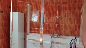 Ein modernes Badezimmer mit einer Duschkabine aus Glas, einem weißen Waschtisch und einer Badewanne.