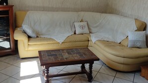 Ein Wohnzimmer mit einem gelben Sofa, einem Holztisch und einer Wanddekoration.