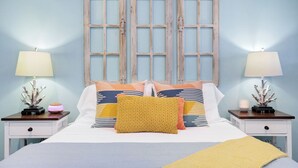 A bed with a white duvet, two nightstands with lamps, and a wooden-framed window. - Romantic~Butterfly Cttg~Central Loc, Firepit ~Oaks (San Antonio)
