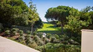 Une vue sur un terrain de golf avec une clôture, des arbres et un lampadaire.