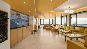 A spacious living area with a large painting, comfortable seating, and a view through large windows. - Days Inn By Wyndham Gangtok Tadong (Gangtok)