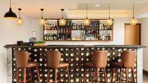 A bar area with a marble countertop, three stools, and a wall of liquor bottles. - Days Inn By Wyndham Gangtok Tadong (Gangtok)
