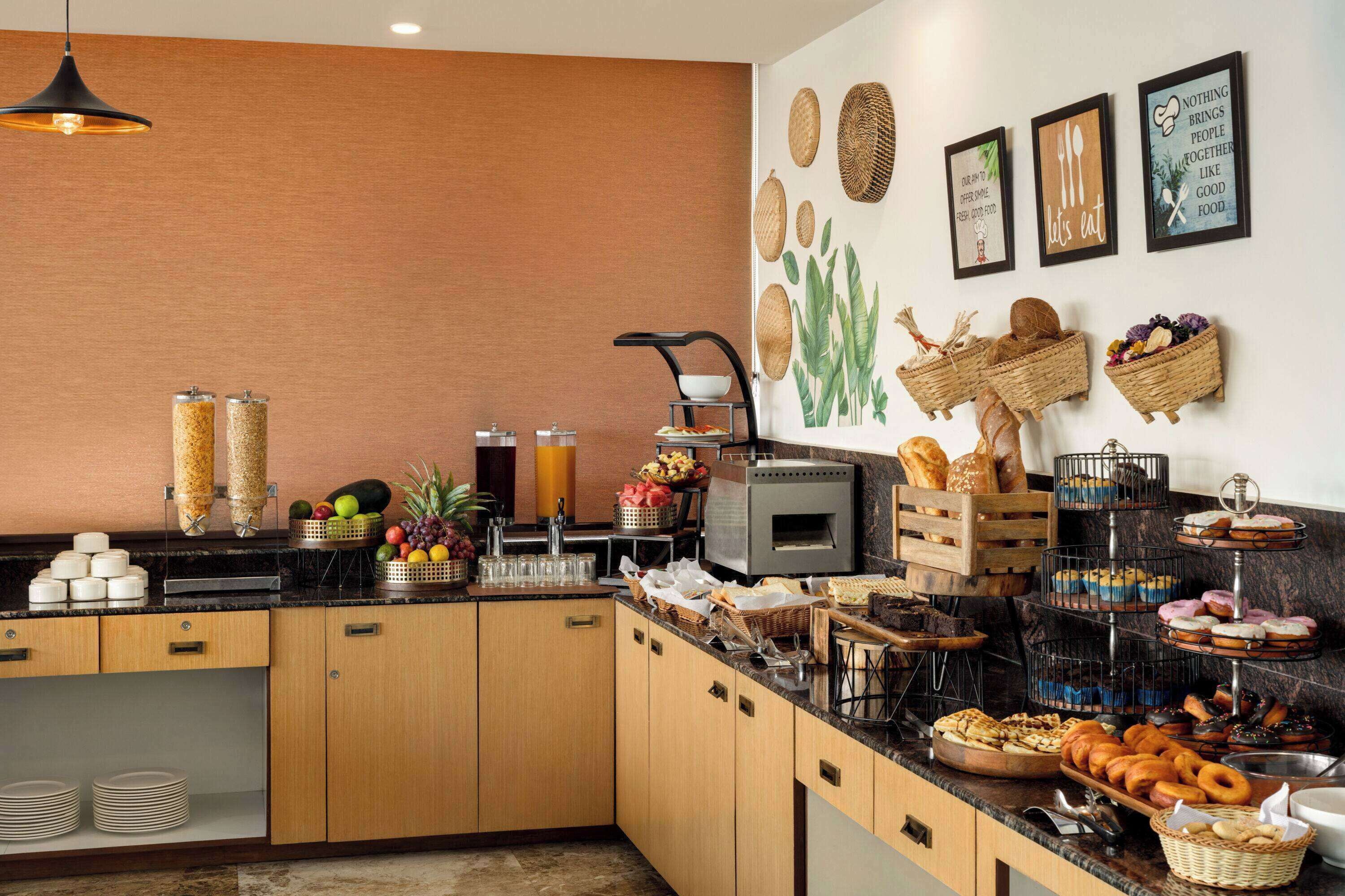 Una cocina moderna con armarios de madera, encimera negra y diversos alimentos exhibidos en la encimera.