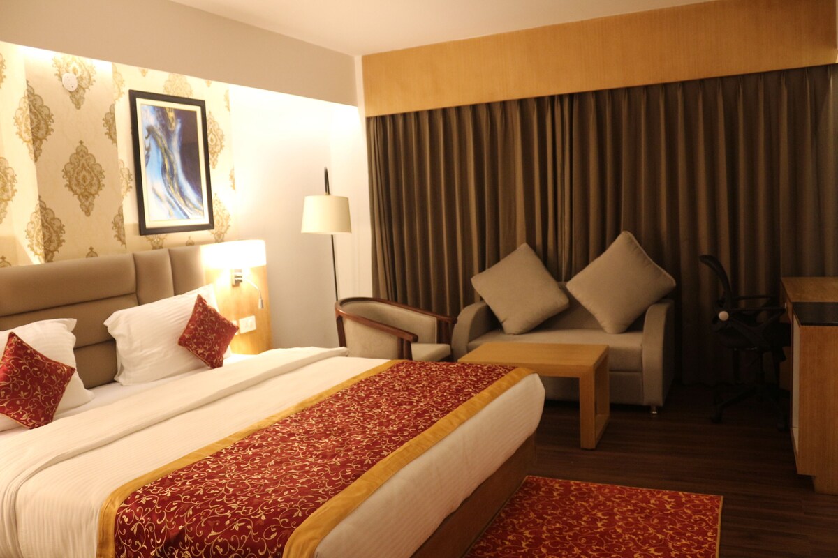Une chambre d’hôtel avec un grand lit, un canapé, un bureau et une chaise.