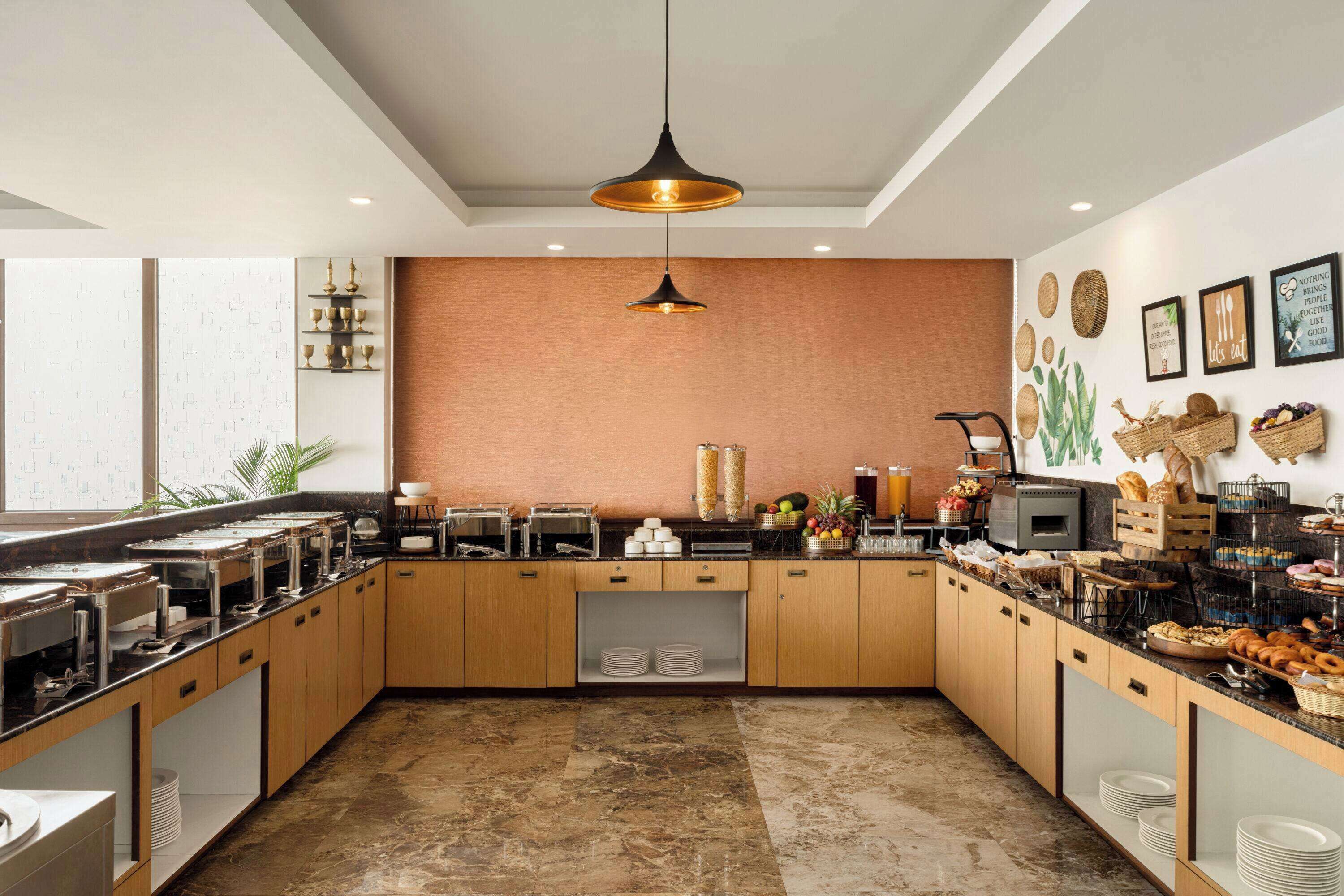 Una cocina moderna con armarios de madera, piso de mármol y diversos productos para el desayuno sobre la encimera.