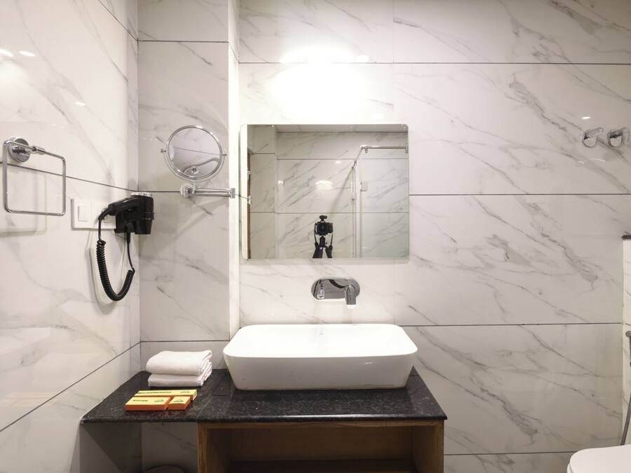 Een moderne badkamer met een wit wastafel, marmeren wanden, een spiegel en een douche.