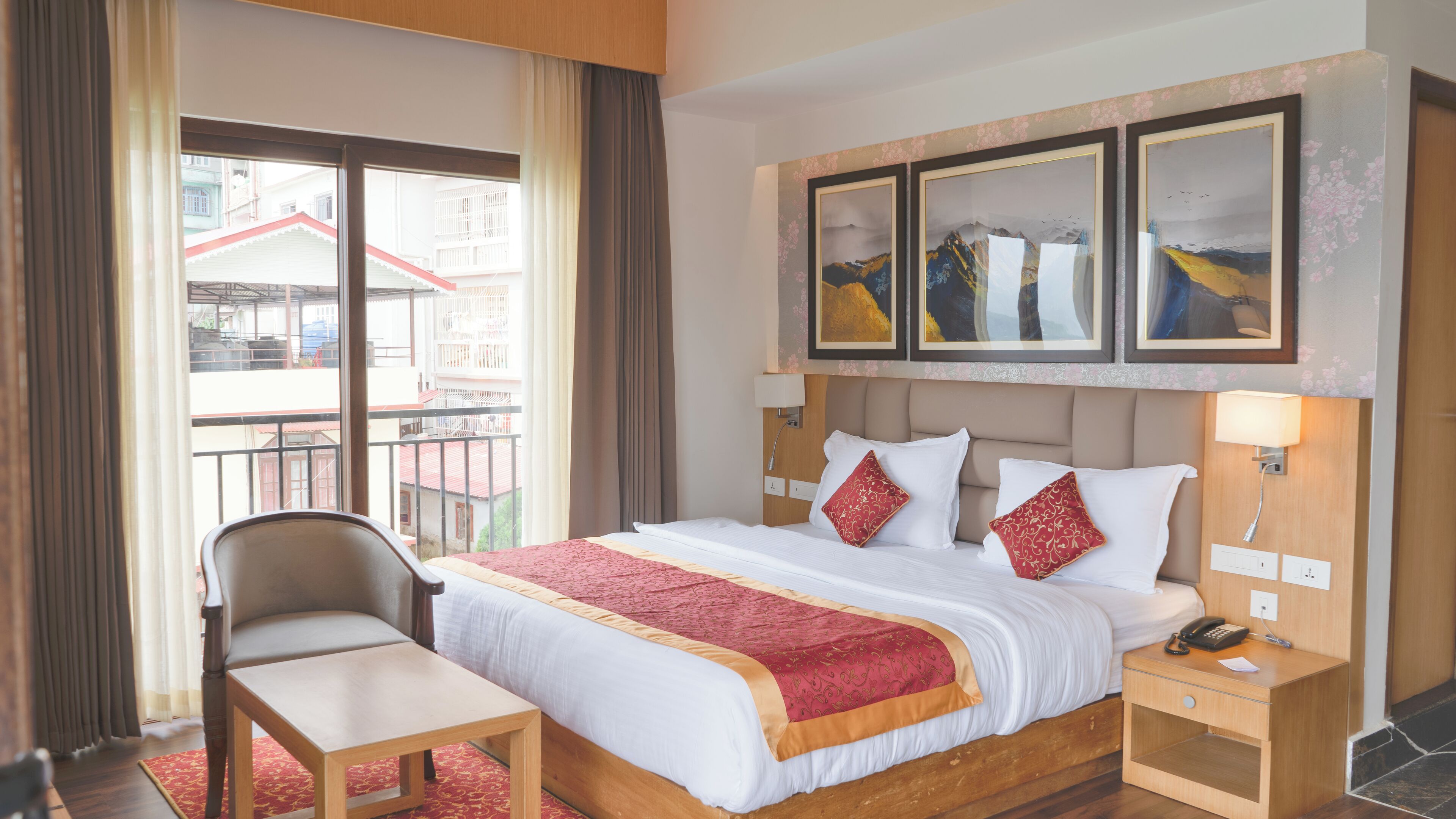 Habitación de hotel con cama, escritorio, silla y balcón con vista a edificios.