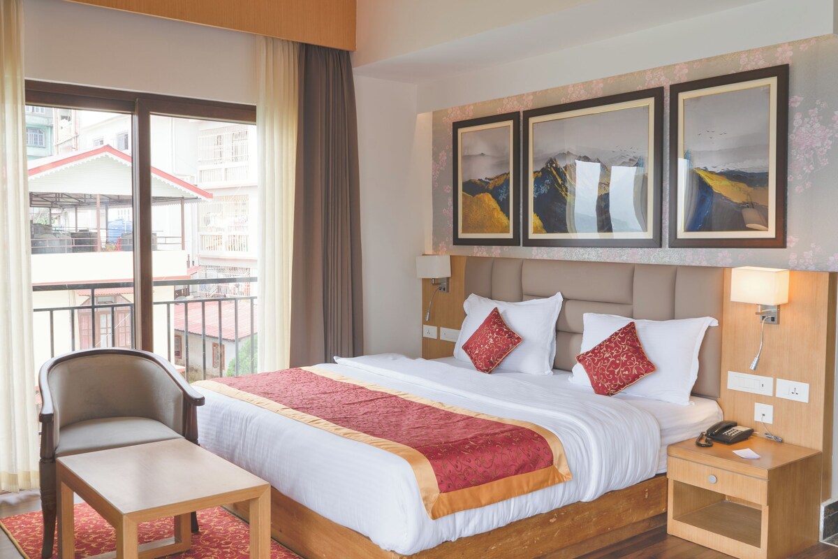 Une chambre d’hôtel équipée d’un lit, d’un bureau, d’une chaise et d’un balcon donnant sur des immeubles.
