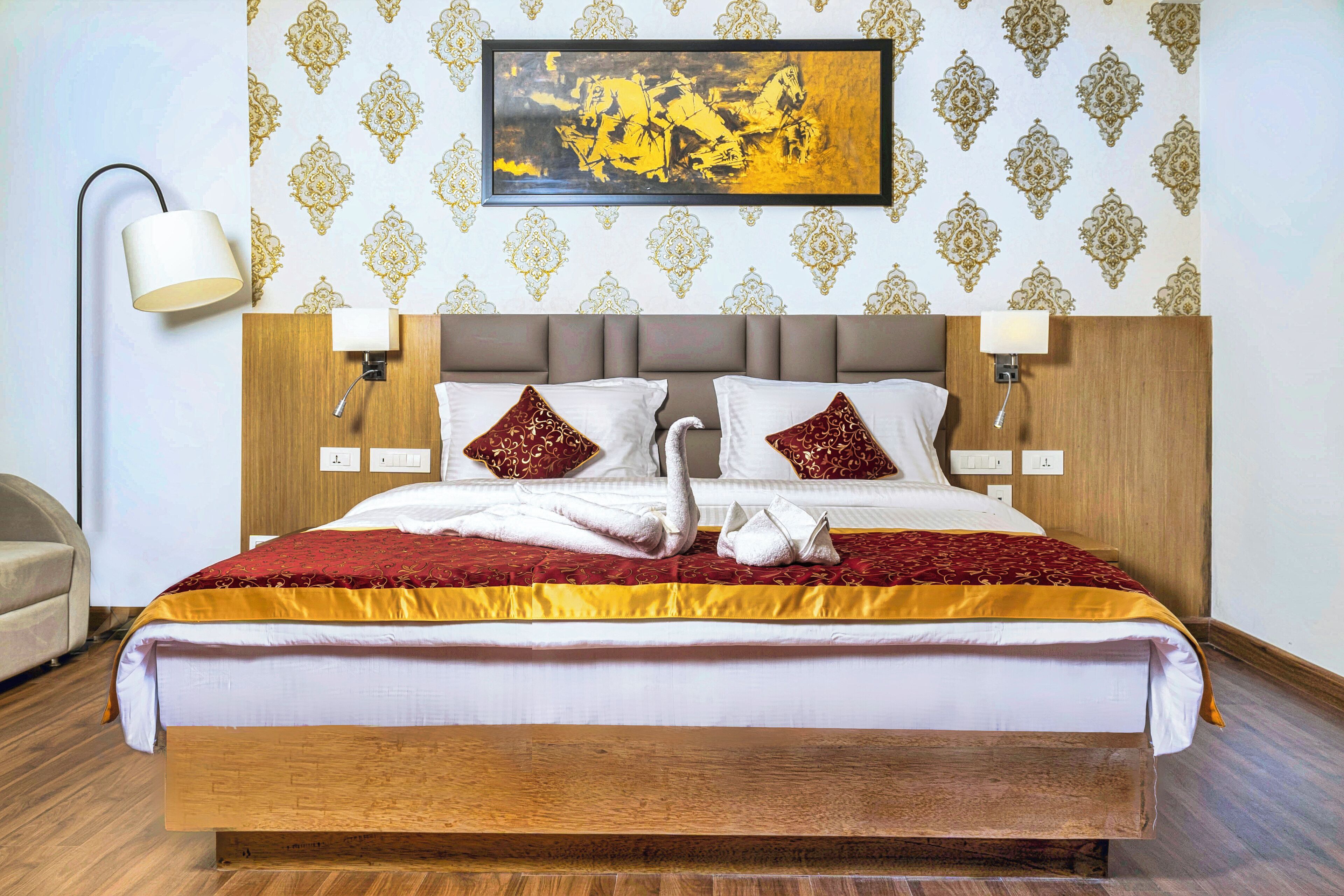 A neatly made bed with a wooden headboard, two wall-mounted lamps, and a framed picture above.