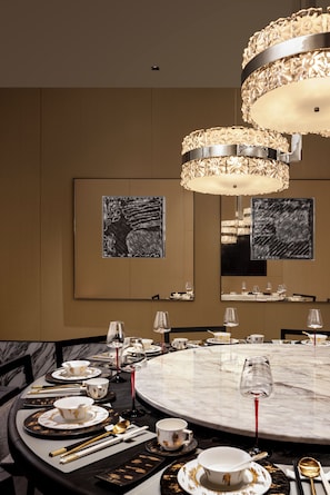 Un coin repas avec une table ronde, des chaises et un lustre.