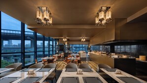 Un restaurant moderne doté de grandes fenêtres, d’une salle à manger centrale et d’un comptoir de cuisine.