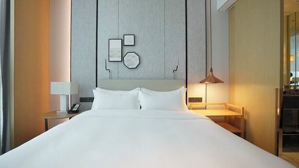 Une chambre d’hôtel avec un grand lit, deux tables de chevet, une lampe et une œuvre d’art accrochée au mur.