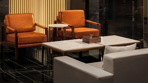 Un intérieur moderne avec des fauteuils en cuir, une table en marbre et des stores verticaux.