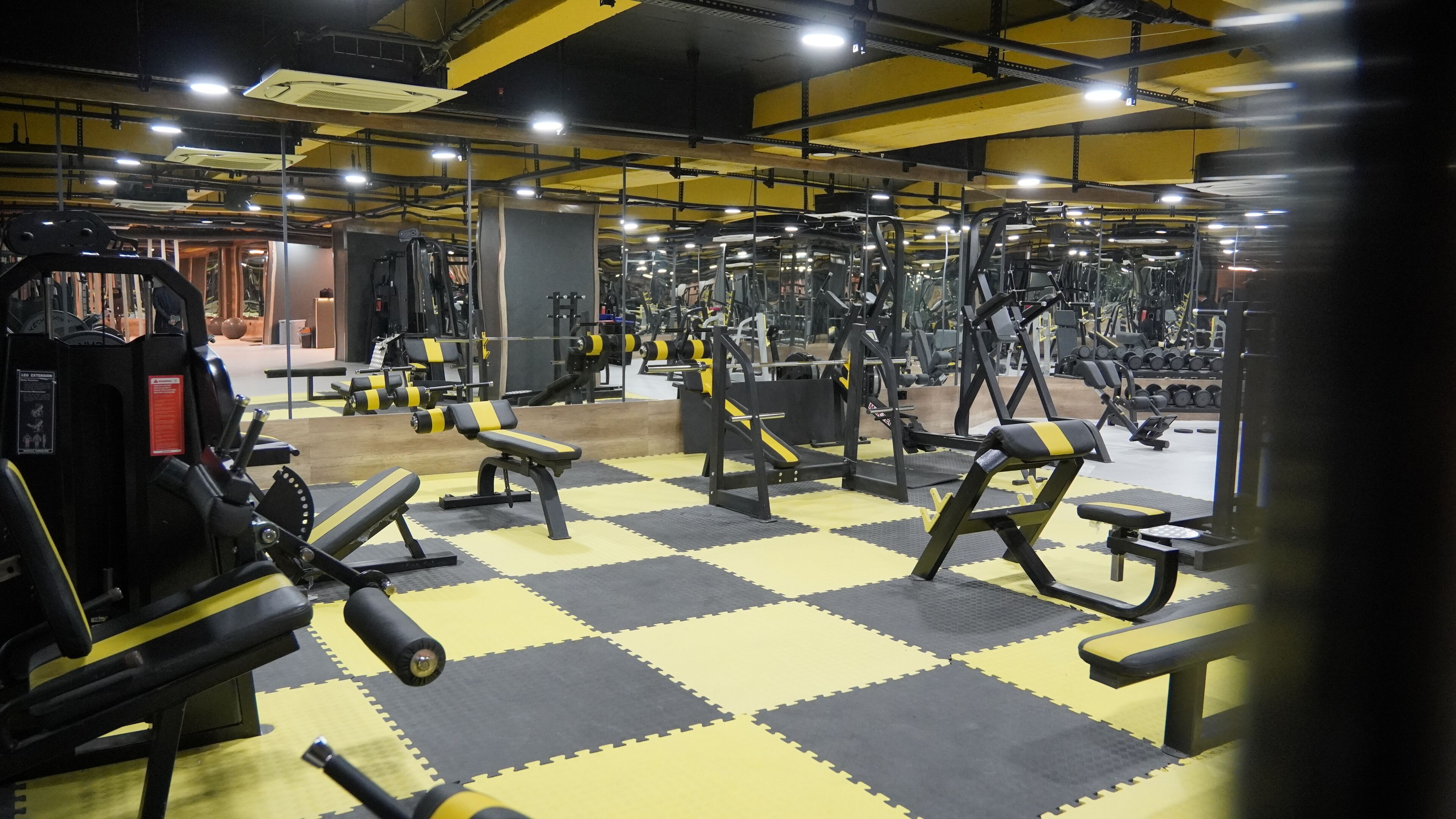 A gym with various exercise equipment, including benches, dumbbells, and weight machines.