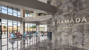 A spacious lobby with a high ceiling, large windows, and a marble wall with the name "RAMADA PLAZA BY WYNDHAM". - Ramada Plaza By Wyndham Batman (Batman)
