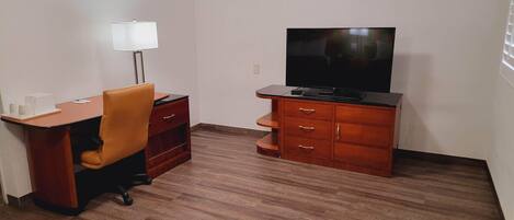 A small room with a wooden desk, a chair, a television, and a cabinet.
