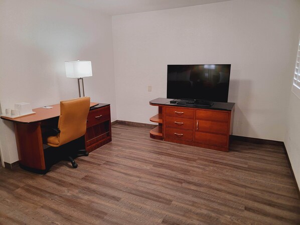 Una habitación pequeña con un escritorio de madera, una silla, un televisor y un armario.