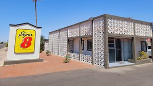 A Super 8 motel with a distinctive white lattice facade, a palm tree, and a clear blue sky. - Super 8 By Wyndham El Centro North (El Centro)