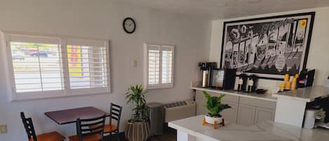 Una cocina moderna con comedor, que cuenta con una encimera blanca, un reloj y un mural grande en blanco y negro.