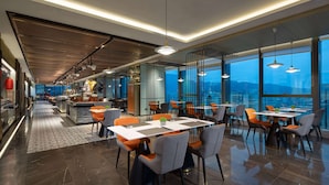 Un restaurante moderno con techos altos, ventanas amplias y diversas opciones de asientos.