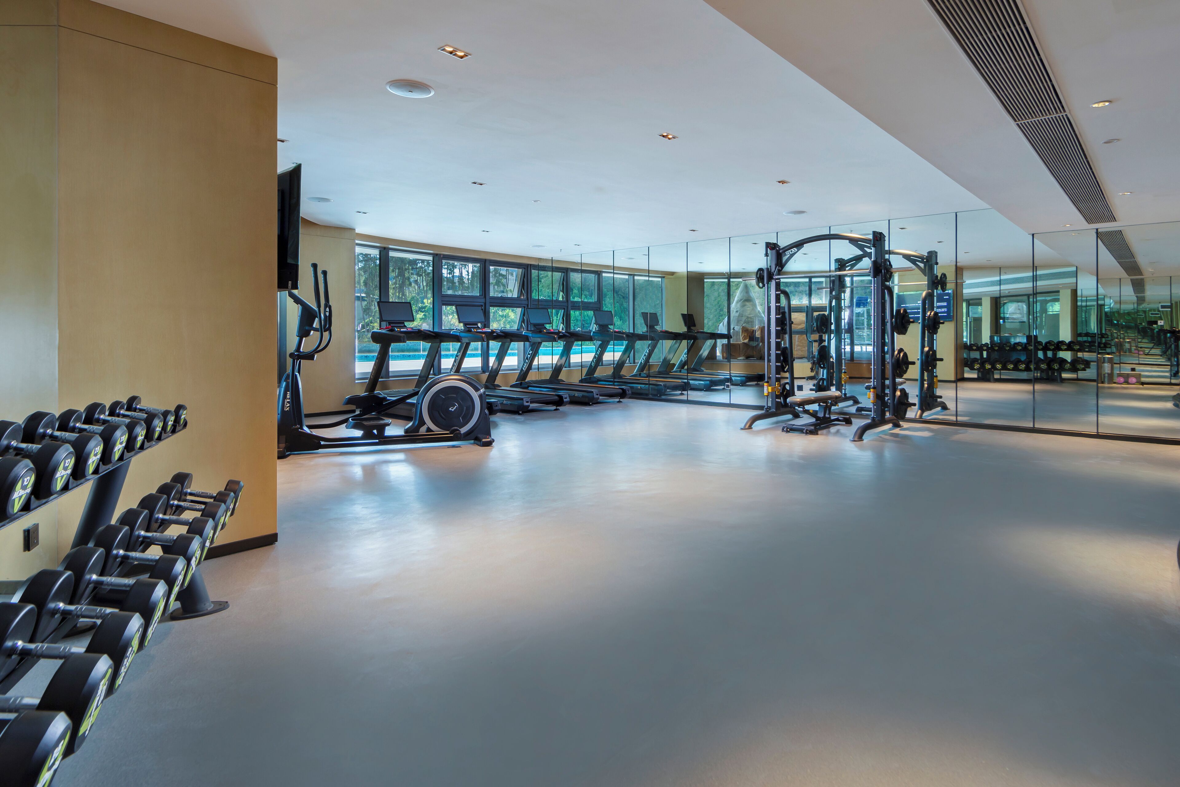 Une salle de sport moderne équipée de tapis de course, d’haltères et d’appareils de musculation.