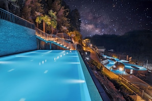 A swimming pool with a night sky view, a staircase, and a building with a unique design. - Wyndham Grand Plaza Royale Hot Springs Fenghuang (Xiangxi)