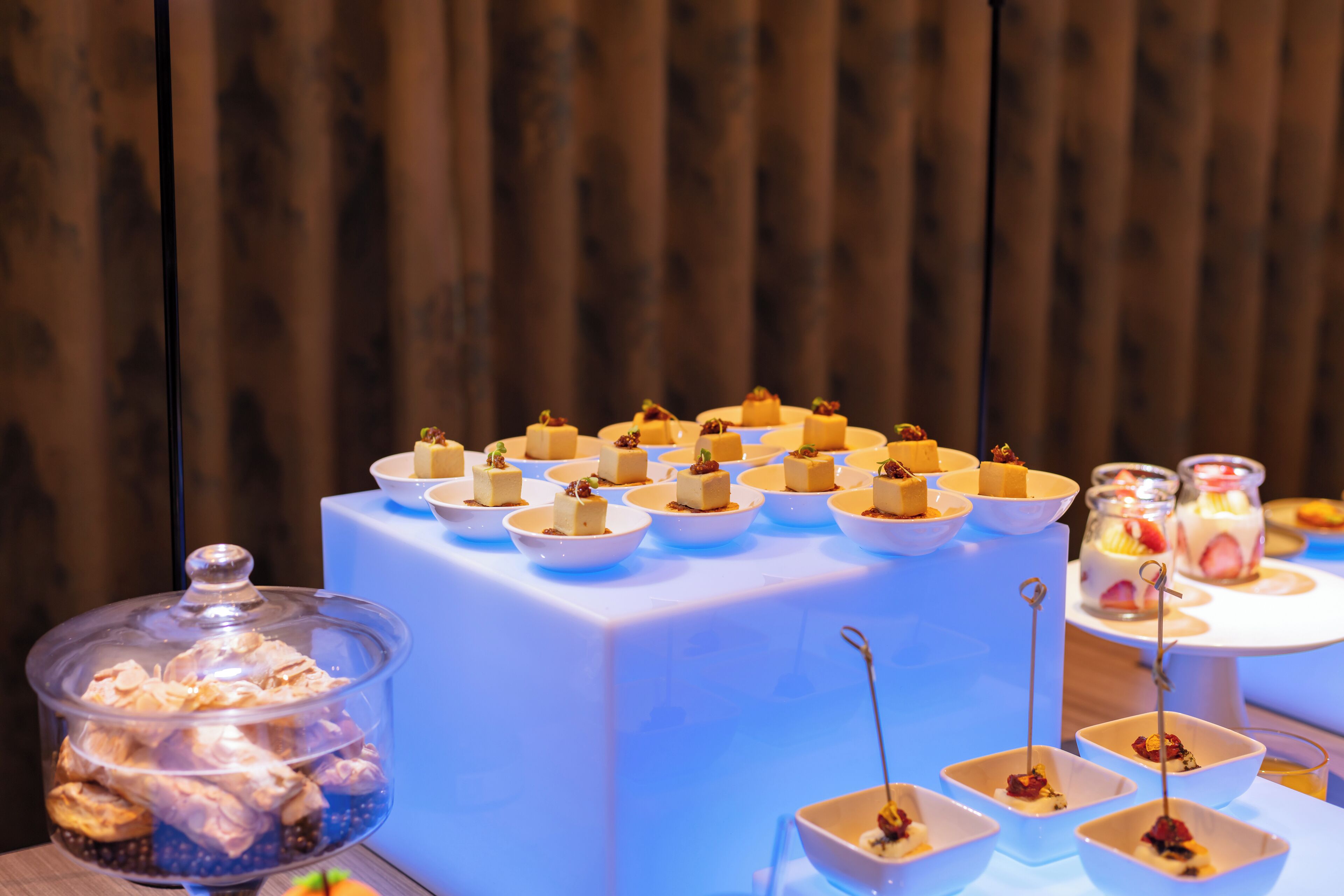 A buffet table with various food items, including desserts and appetizers, arranged on white plates and bowls.