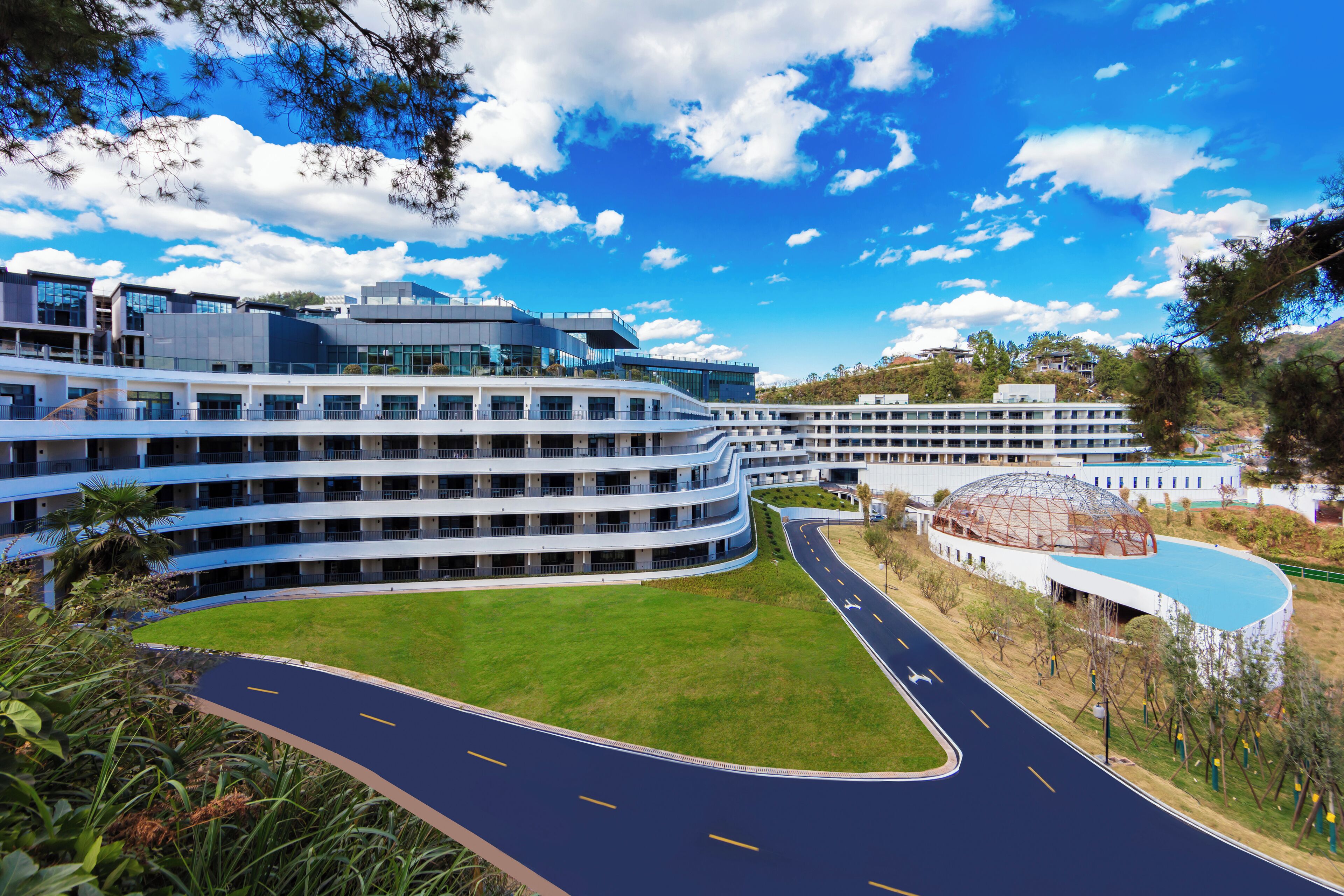 A modern building with multiple floors and a curved road in front.