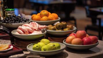 Een tafel met verschillende soorten fruit en groenten, zoals sinaasappels, appels en avocado's.