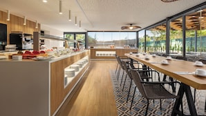 A modern kitchen with a long counter, wooden cabinets, and a view of the outdoors. - Wyndham Residences Alvor Beach (Portimão)