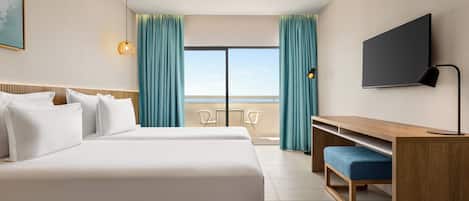 A hotel room with a large bed, a desk, a TV, and a balcony with curtains.
