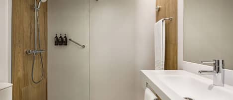 A modern bathroom with a shower, toilet, and sink.