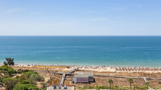 A beach with a pier and a building in the foreground. - Wyndham Residences Alvor Beach (Portimão)