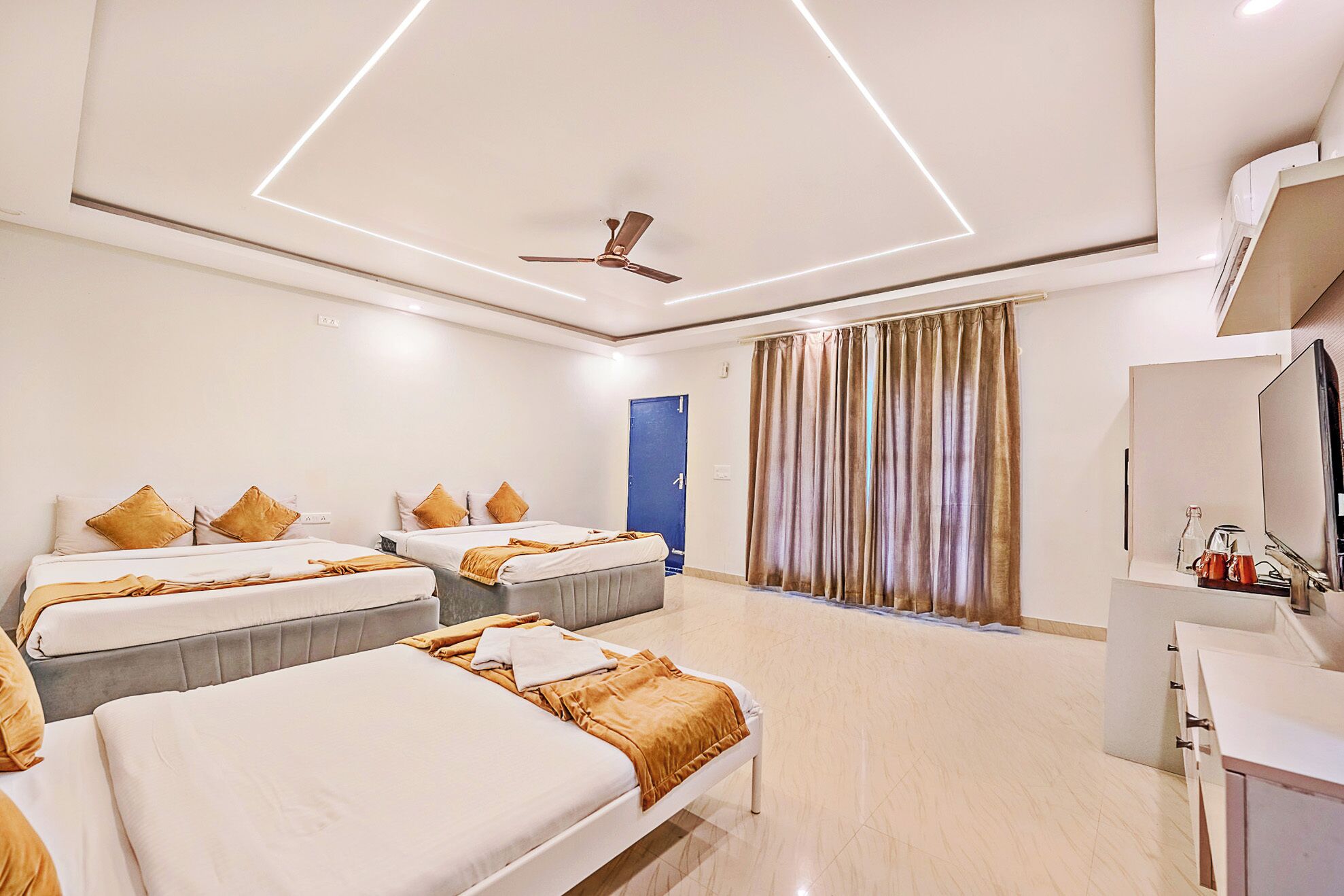 A hotel room with two beds, a ceiling fan, a TV, and a bathroom with a shower.