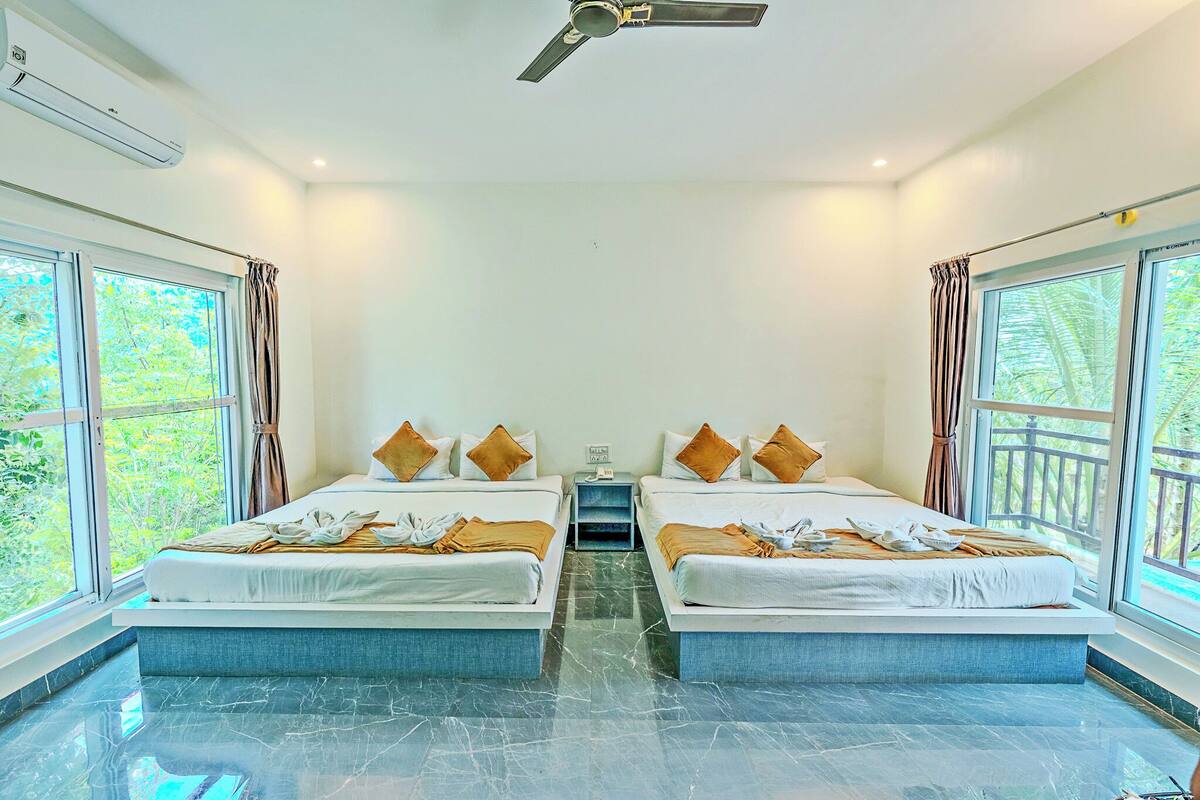 Une chambre d’hôtel avec deux lits, un ventilateur de plafond et de grandes fenêtres avec des rideaux.