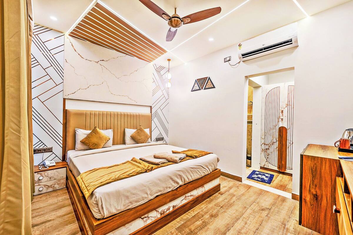 Une chambre moderne avec un lit en bois, un ventilateur de plafond et un mur décoré d’un motif imitant le marbre.