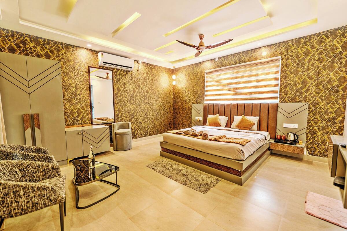 Une chambre moderne avec un grand lit, une coiffeuse, une chaise et un ventilateur de plafond.