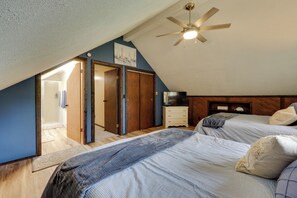Ein Schlafzimmer mit zwei Betten, einem Deckenventilator, einem Fernseher und einem Holzschrank.