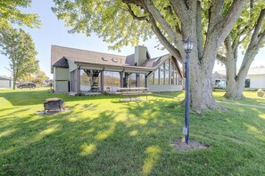 A house with a covered patio, a lawn, and a large tree.