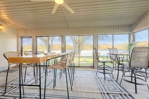 Een overdekt terras met uitzicht op een meer en bomen.