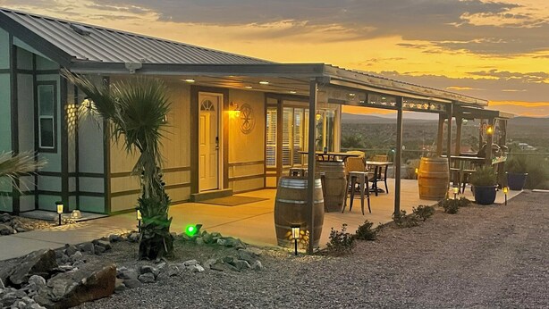 A modern building with a covered patio area, outdoor seating, and a view of the landscape. - Elephant Lake Sunset Oasis (Elephant Butte)